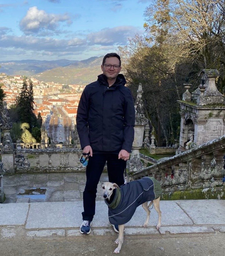 Russell with his dog on outdoor stone steps overlooking a town